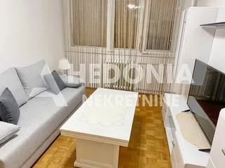 Dnevna soba sa garniturom za sedenje, stočićem i televizorom.