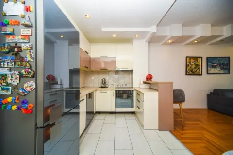 Kitchen equipped with cabinetry and appliances, featuring a breakfast bar separating it from the living room. - image 5