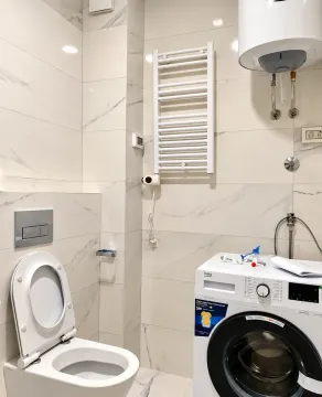 Svijetlo kupatilo sa bijelim pločicama, wc šoljom, mašinom za veš i bojlerom. - image 7
