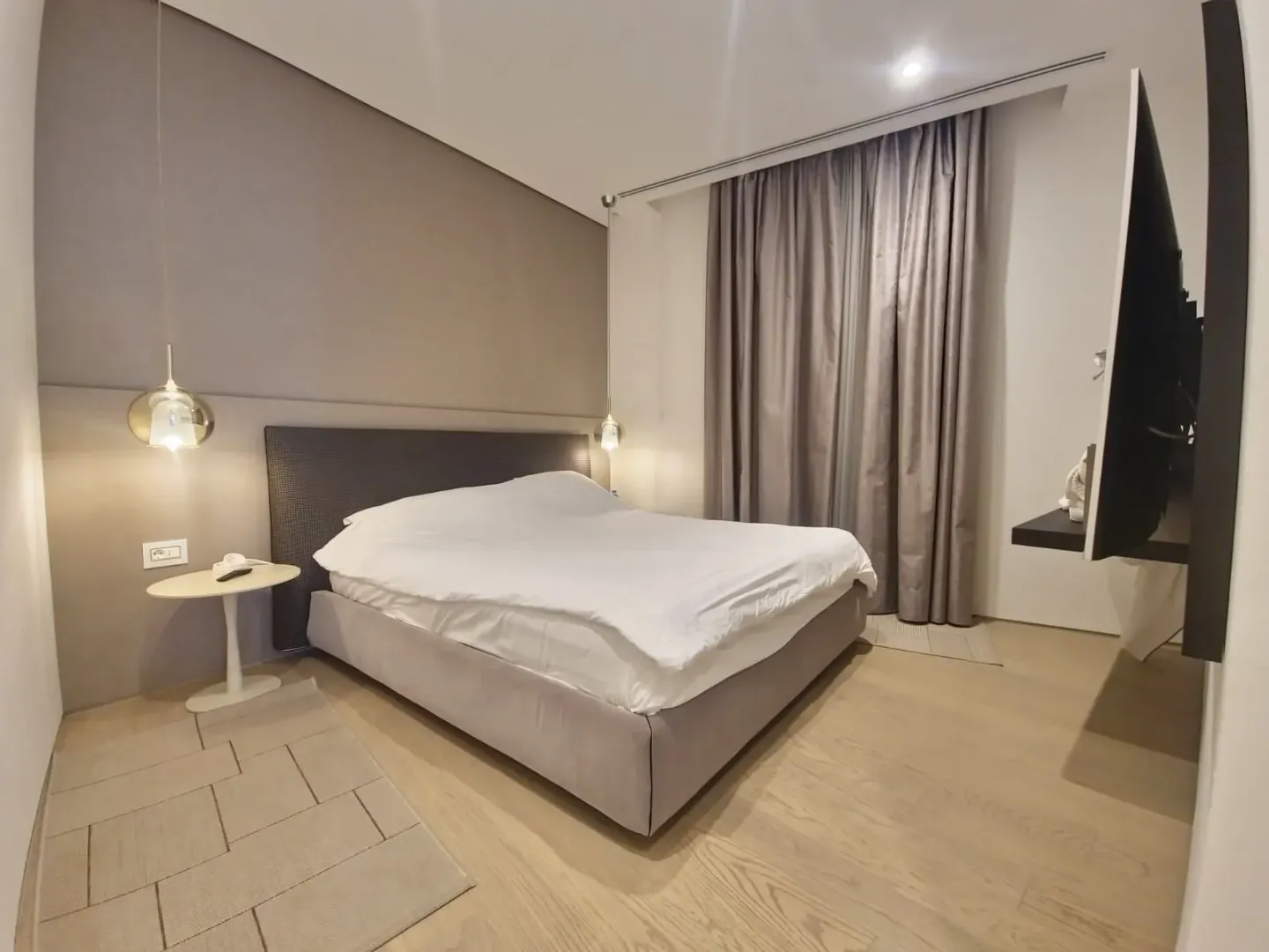 Modern bedroom with a double bed, bedside tables, and a television.