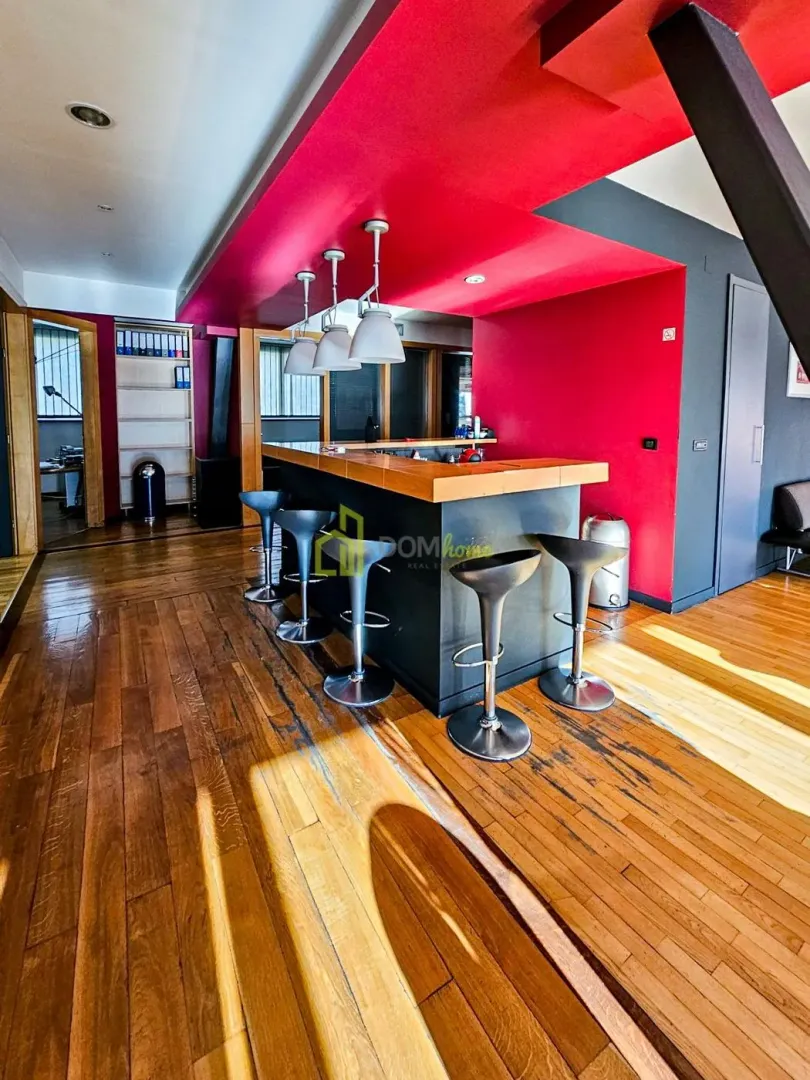 Kitchen with a bar counter and bar stools, red walls, and hardwood flooring.