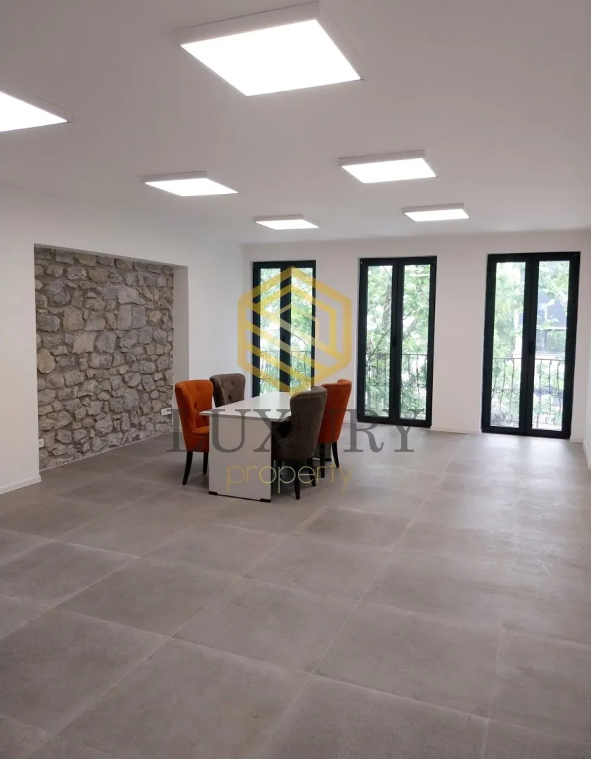 Spacious living room with a dining table and chairs, modern lighting, and a stone accent wall.