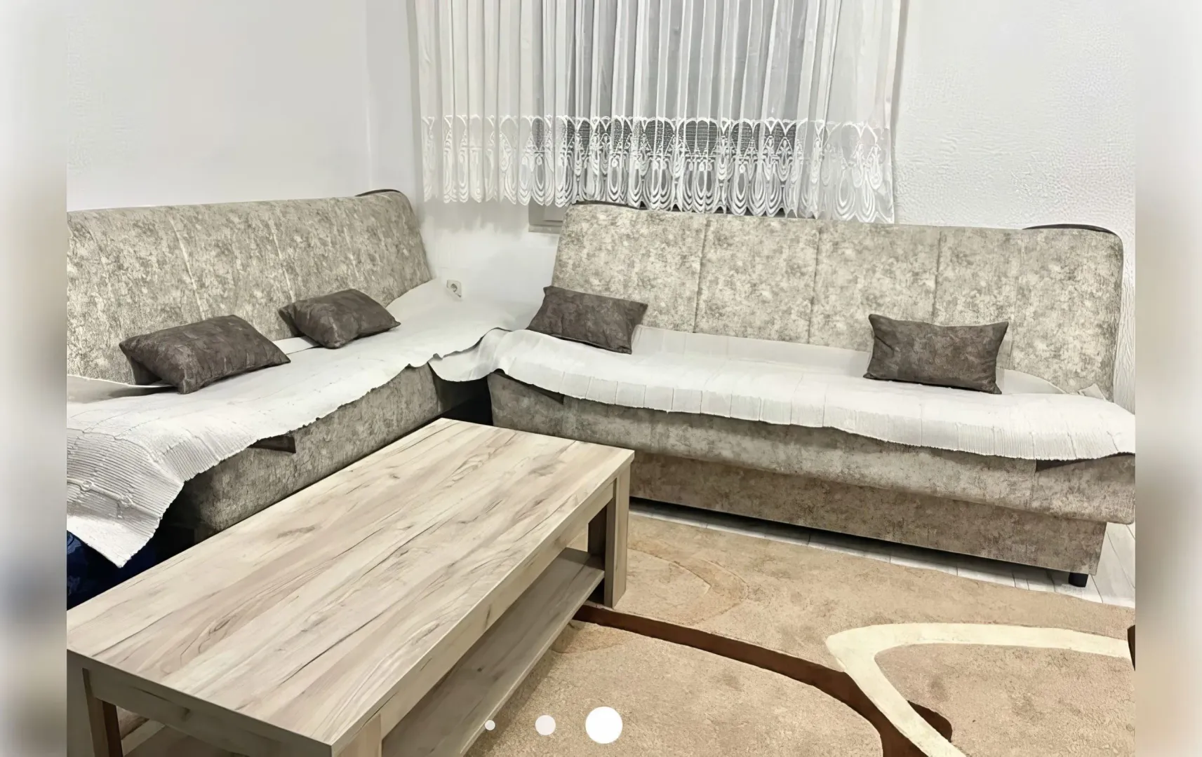 Dnevna soba sa garniturom za sjedenje i drvenim stočićem.