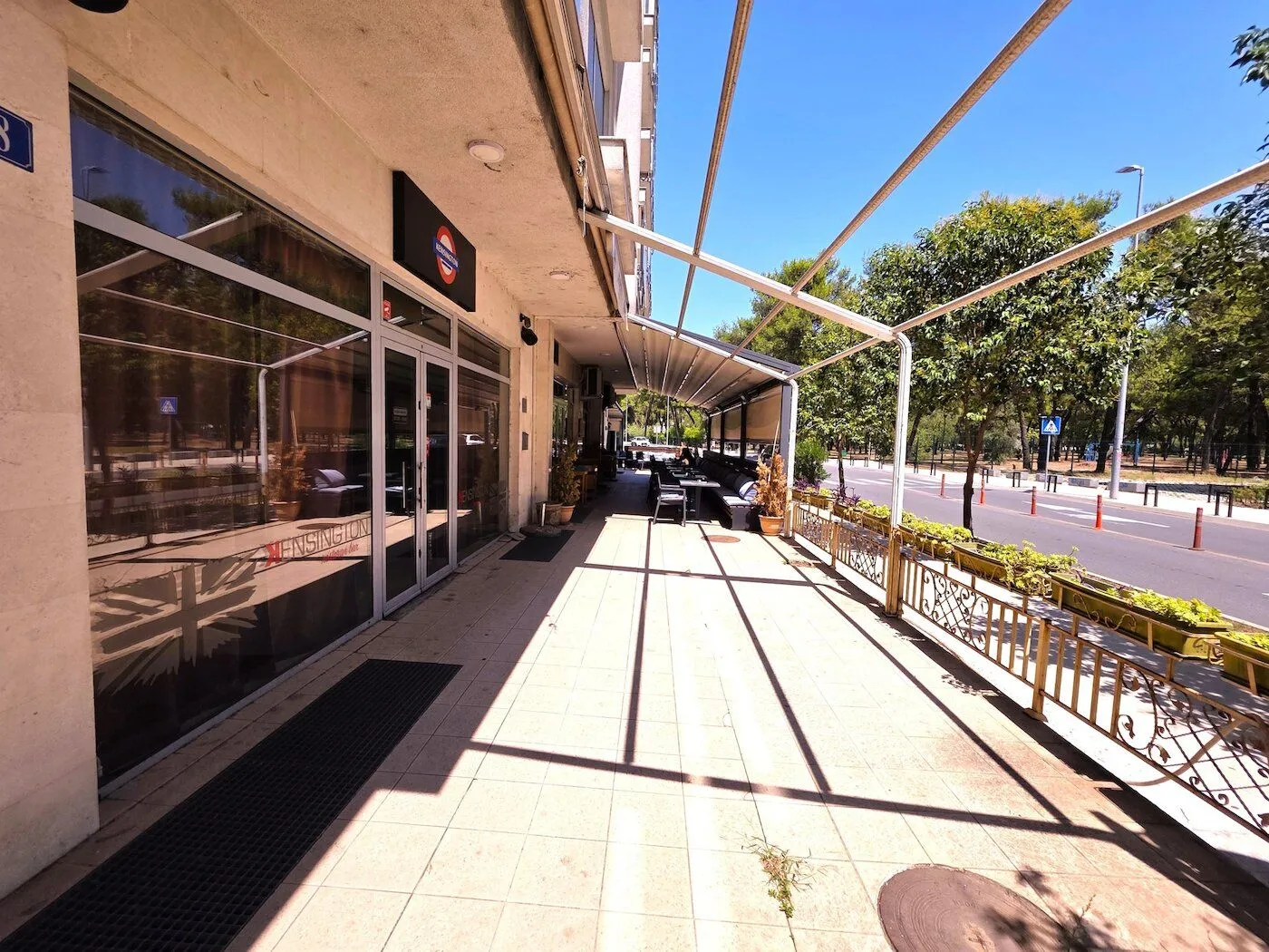 Exterior of a commercial space with a paved terrace and canopy along the street.