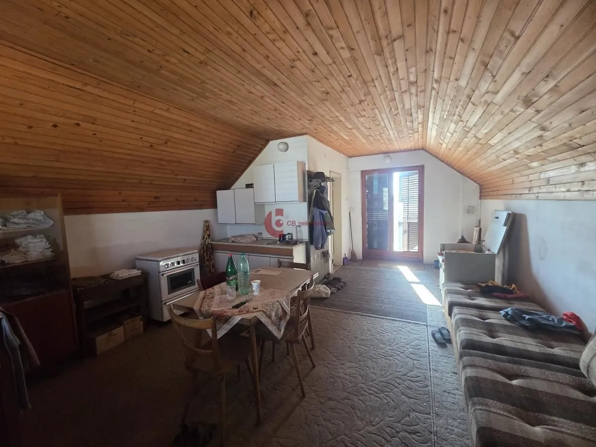 Manja kuhinja sa trpezarijskim stolom u potkrovlju sa drvenim plafonom.