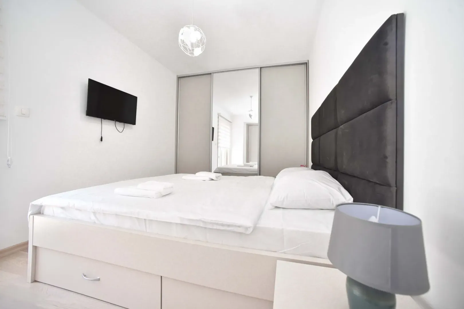 Bedroom with a double bed, mirrored wardrobe, and wall-mounted television.