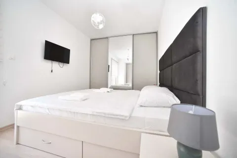 Bedroom with a double bed, mirrored wardrobe, and wall-mounted television. - image 21
