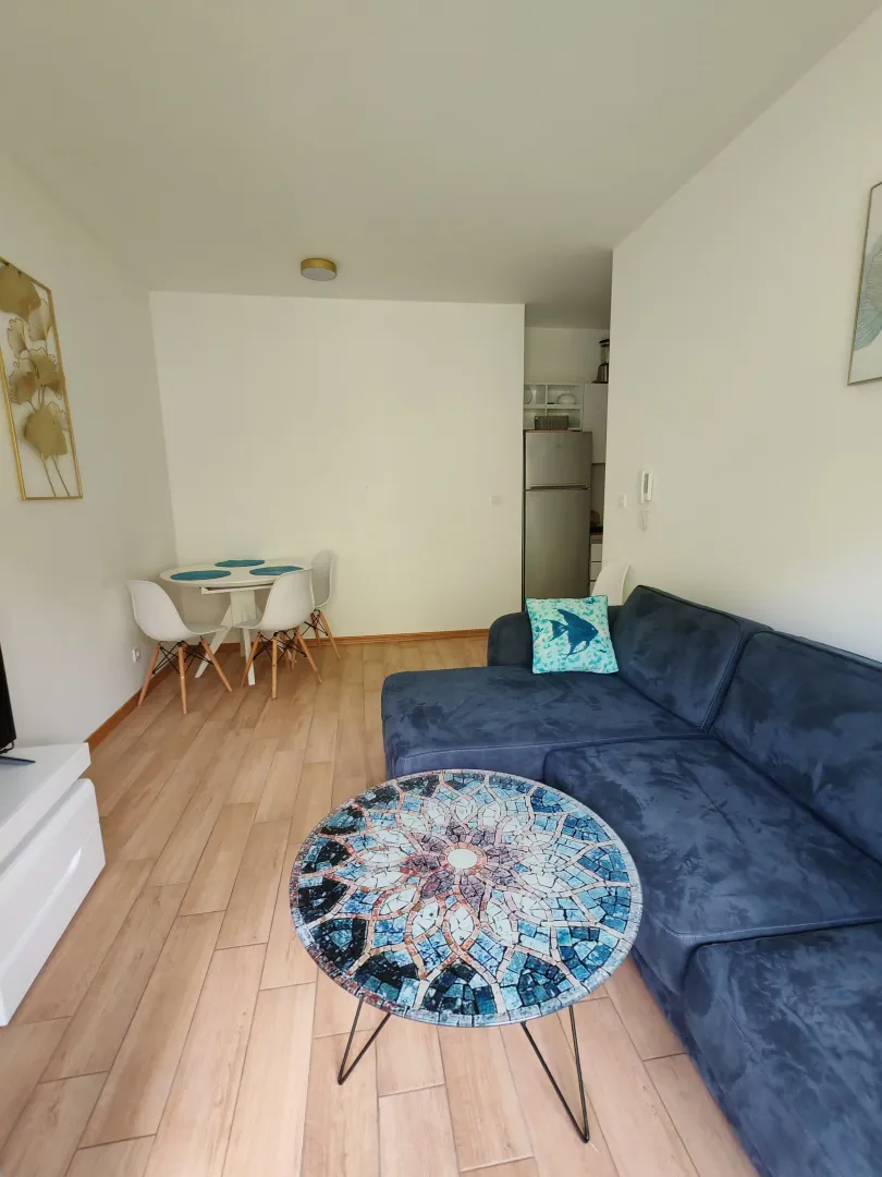 Living room with a sofa, coffee table and dining table.