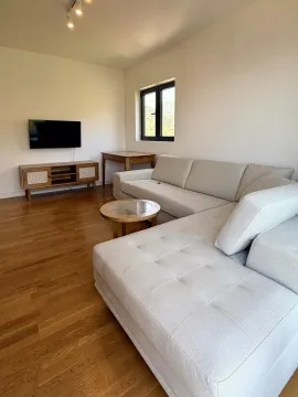 Dnevna soba sa ugaonom garniturom, stočićem i TV-om na zidu. - image 2