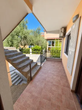 Covered terrace with tiled flooring and stairs leading to the upper floor. - image 6