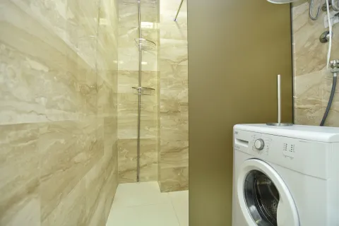 Tiled bathroom with a shower enclosure and a washing machine. - image 13