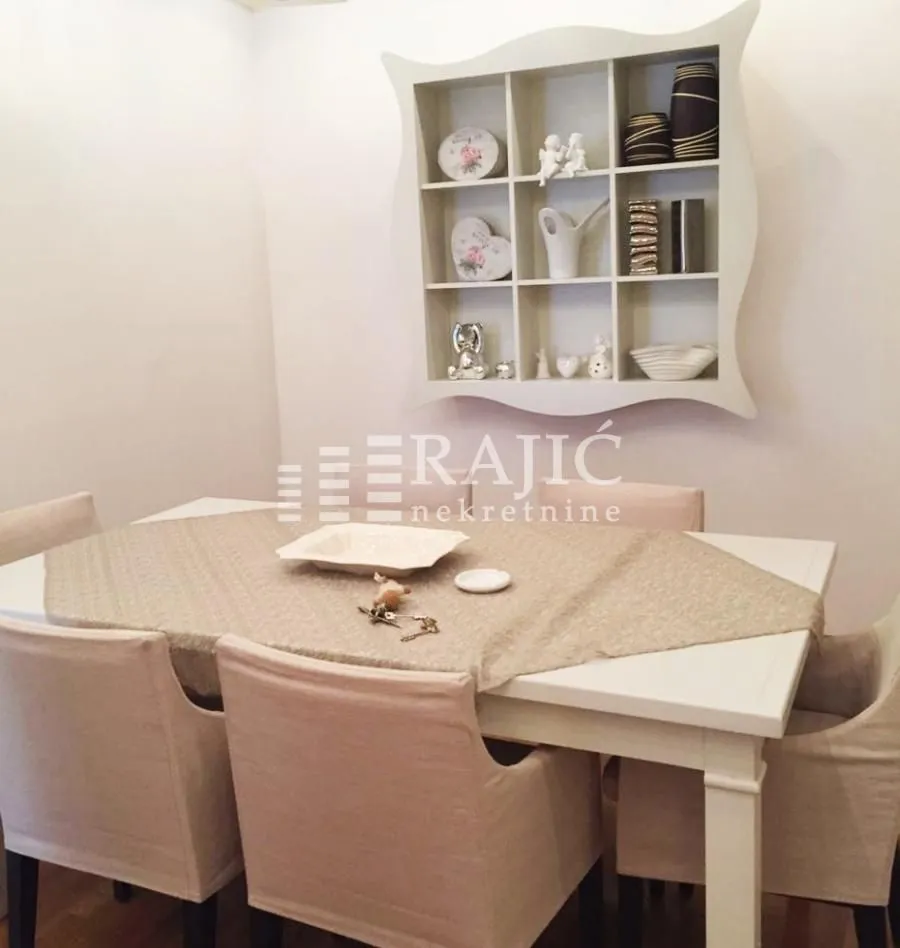 Dining room with a white table, chairs, and a wall shelf.