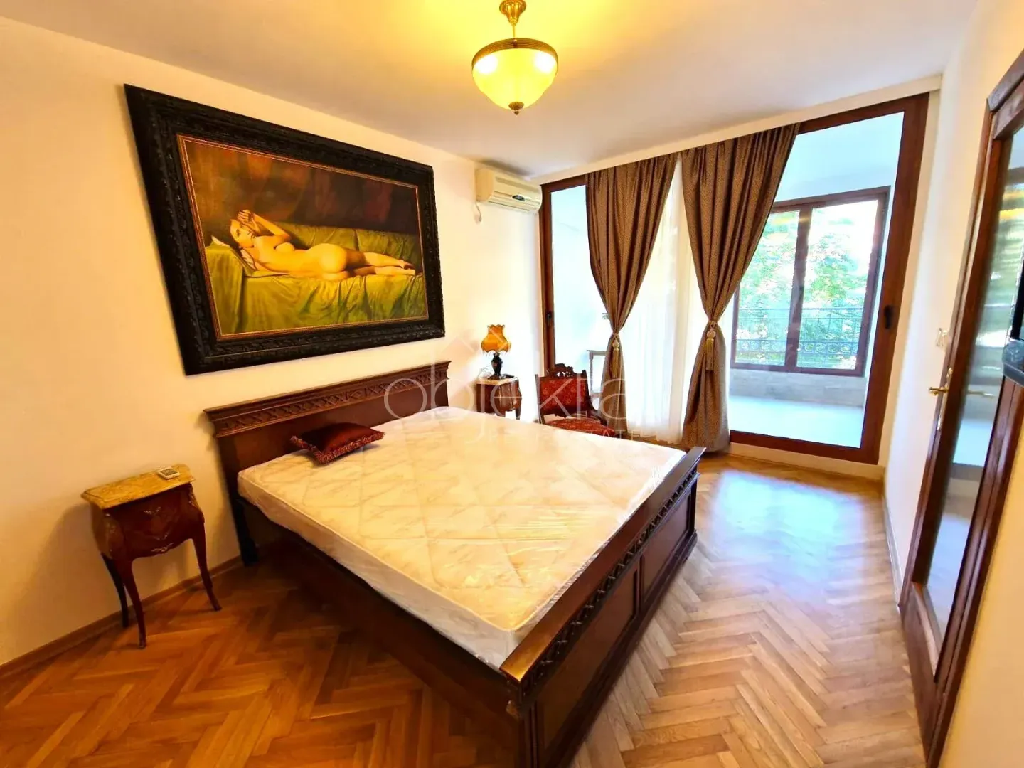 Bedroom with a double bed, a large painting on the wall, and access to the terrace.