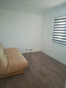 Living room with a beige sofa, small side table, and a window with blinds. - image 5