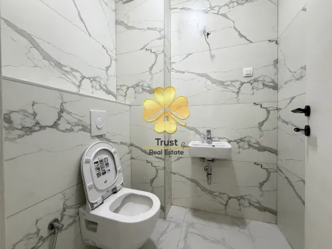Small bathroom lined with marble tiles featuring a toilet and a sink. - image 8