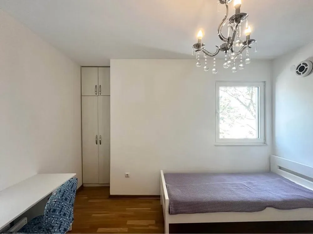 Furnished bedroom with a bed, desk, and built-in wardrobe.