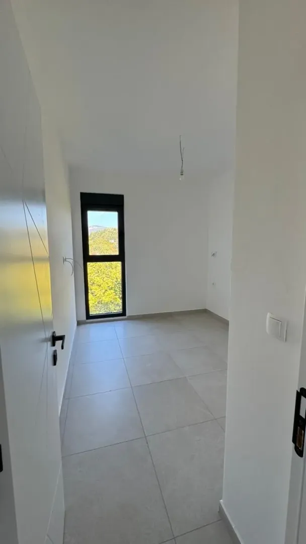 Prazna soba sa pločicama na podu i prozorom.