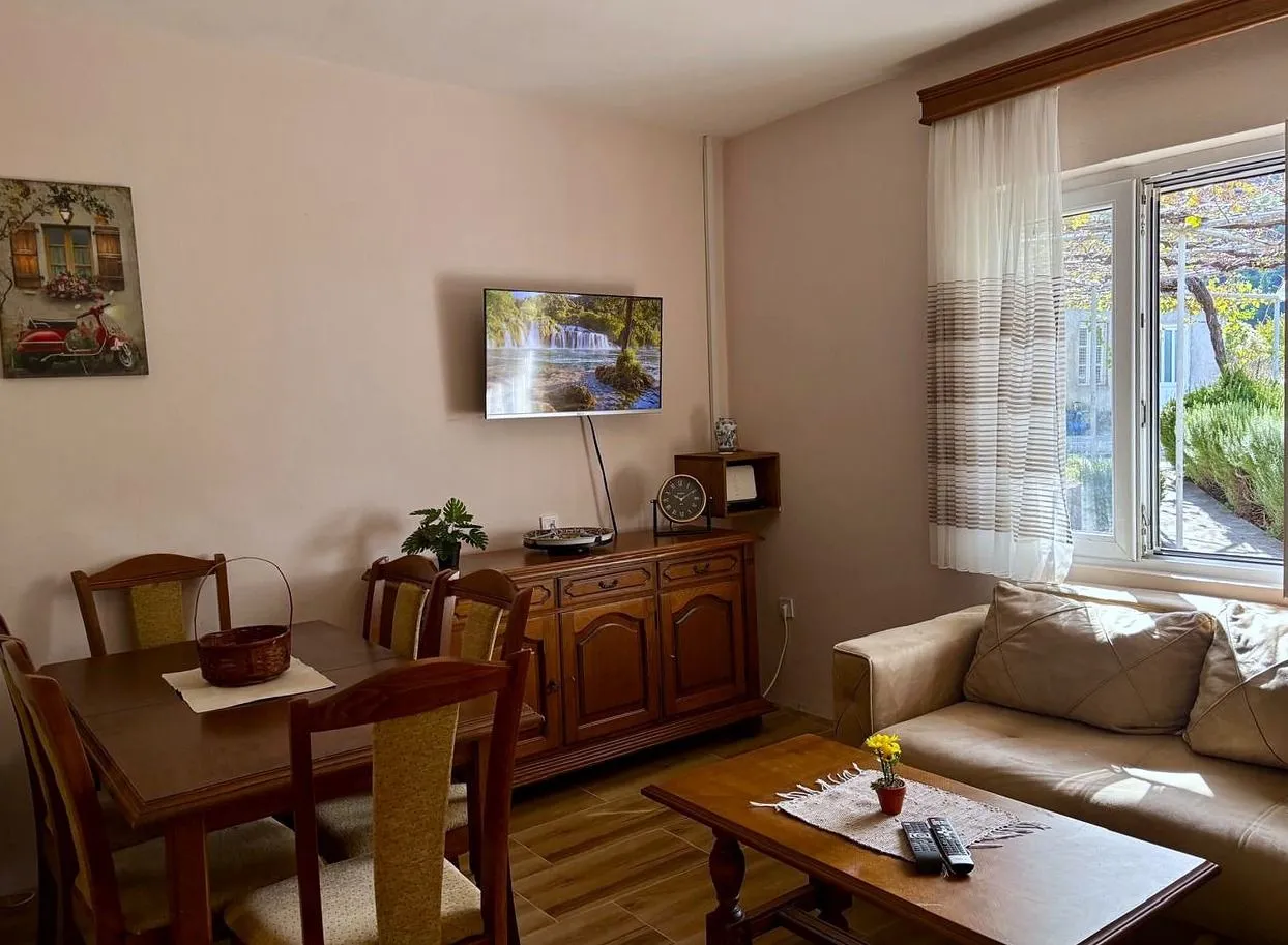 Living room with a sofa, dining table, and wall-mounted TV.