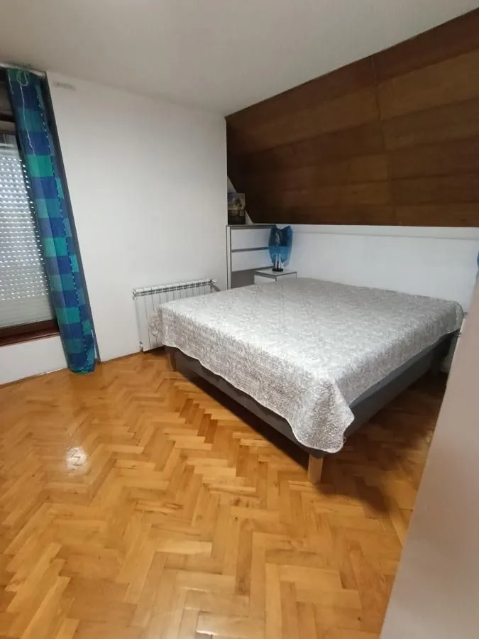 Spavaća soba sa bračnim krevetom i parketom na podu.