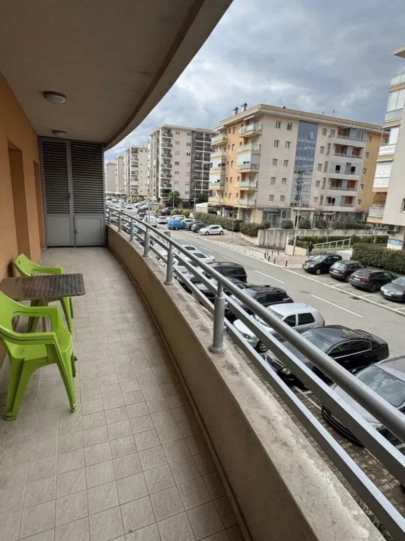 Dugačka popločana terasa sa garniturom za sjedenje i pogledom na ulicu i zgrade.