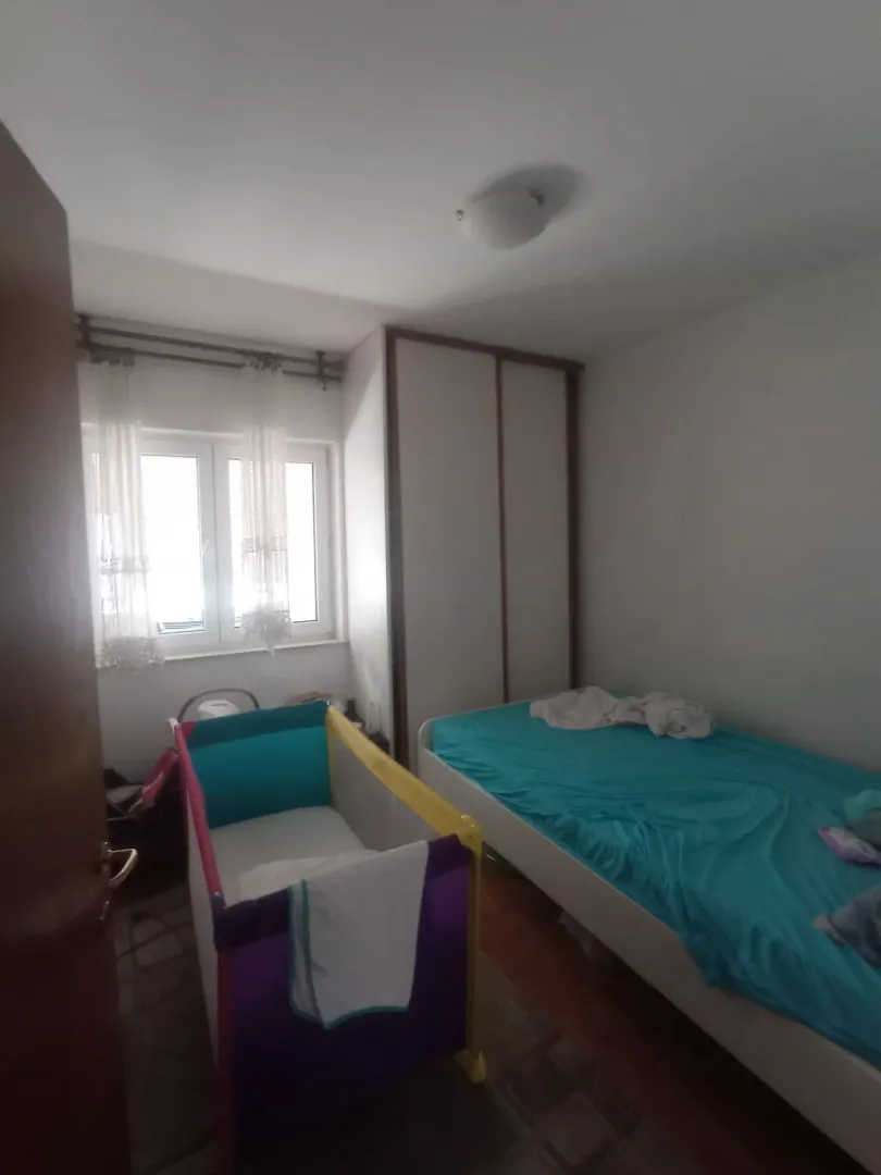 Spavaća soba sa krevetom i dječijim krevecom pored prozora.