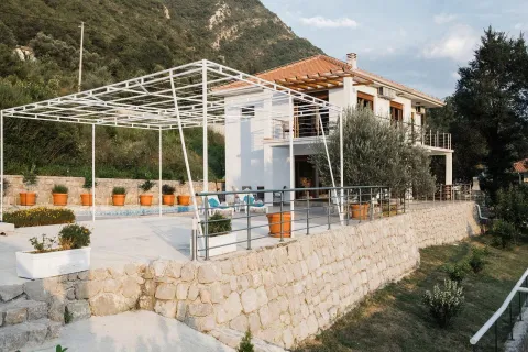 Exterior of a two-story house with a swimming pool, terrace, and stone wall. - image 20