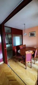 Dining area with a wooden table and chairs, overlooking the kitchen through a partition wall. - image 2