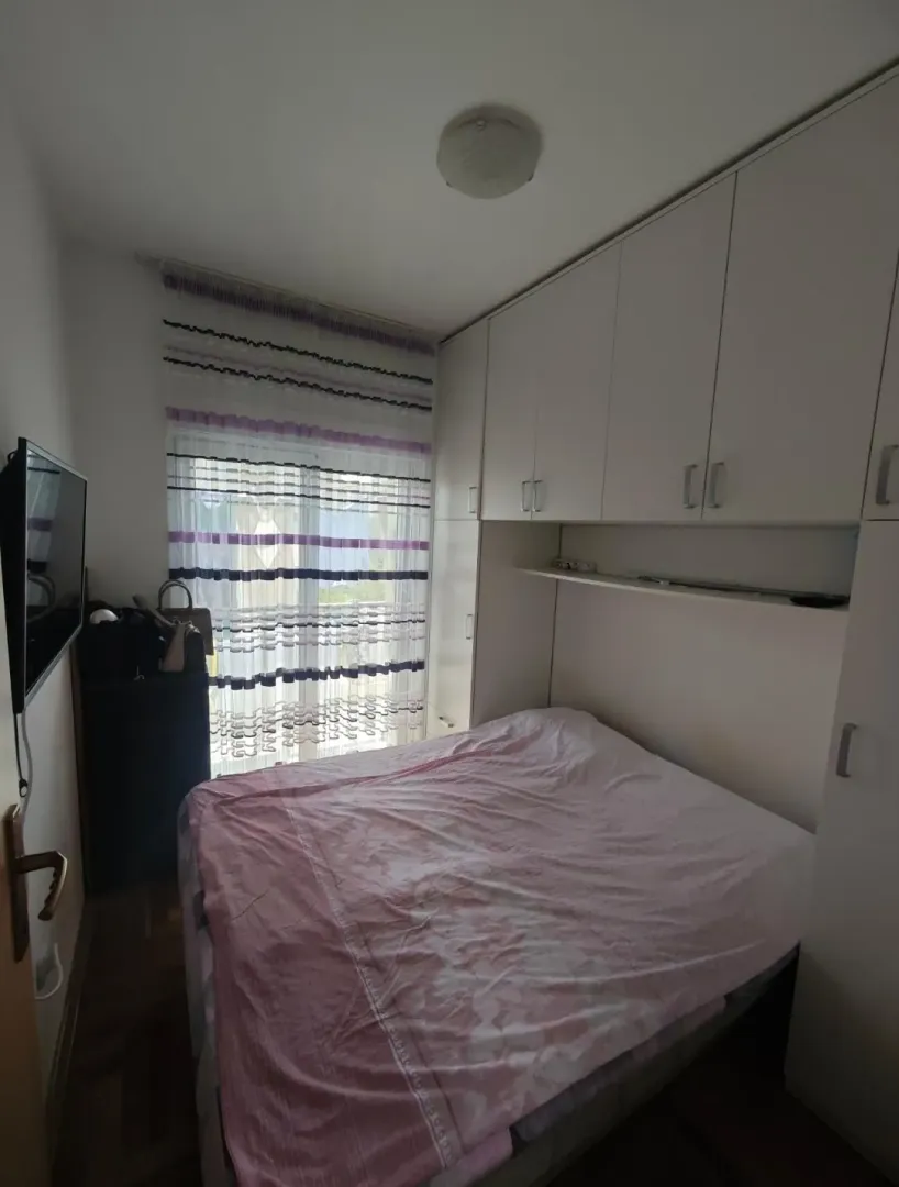 Manja spavaća soba sa bračnim krevetom i ugradnim plakarima.
