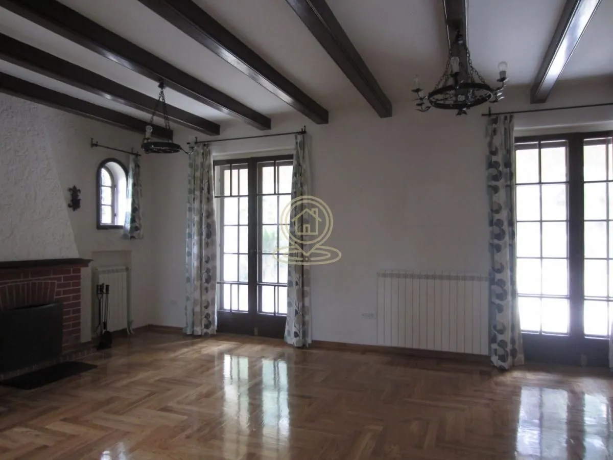 Spacious living room with a fireplace and wooden ceiling beams.