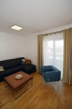Bright living room with a dark sectional sofa and blue armchair. - image 4