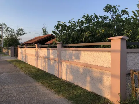 A concrete and metal fence around a yard with greenery in the background. - image 22