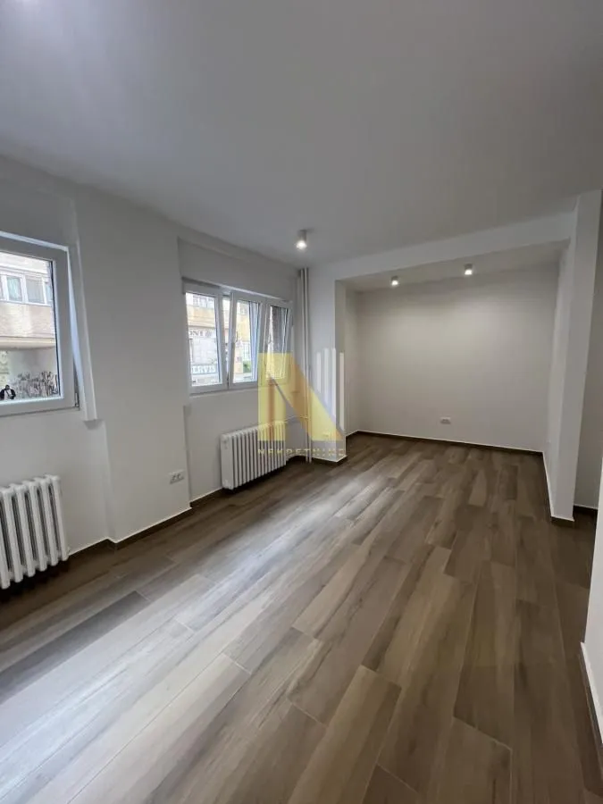 Empty room with light walls and wooden flooring.