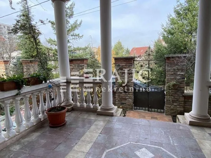 Covered terrace with columns and a view of the courtyard and fence.