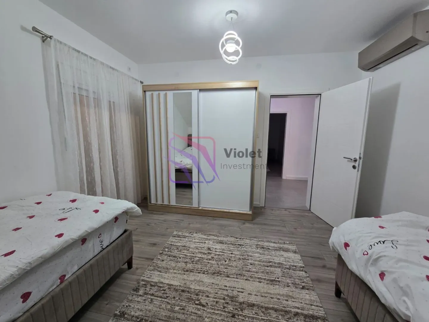 Bedroom with two beds, wardrobe, and a rug.