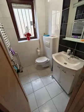 Manje kupatilo sa belim pločicama, umivaonikom i WC šoljom. - image 16