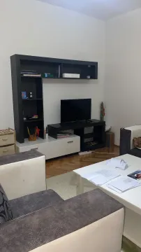 Living room with a sofa, TV, and shelves. - image 4