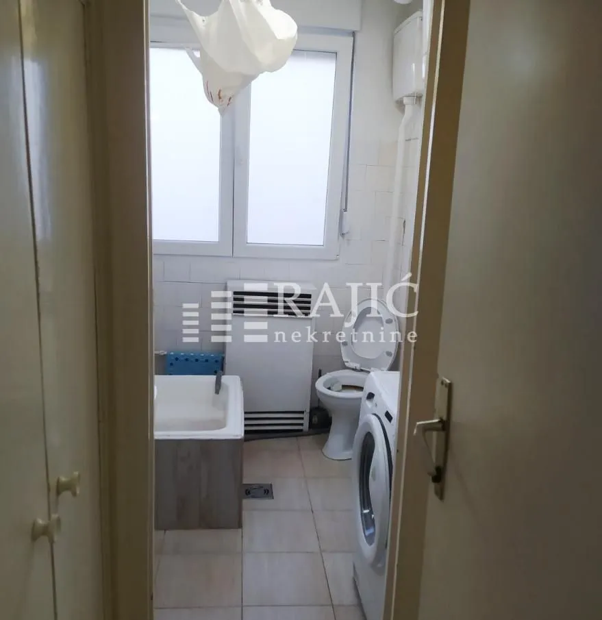 View from the hallway into an older equipped bathroom with a bathtub and washing machine.