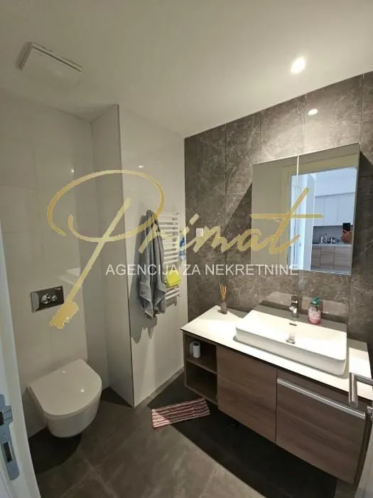 Modern bathroom with a washbasin, a mirror, and a wall-mounted toilet.
