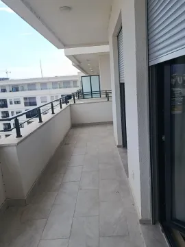 Spacious balcony with tiled flooring and a view of surrounding buildings. - image 8