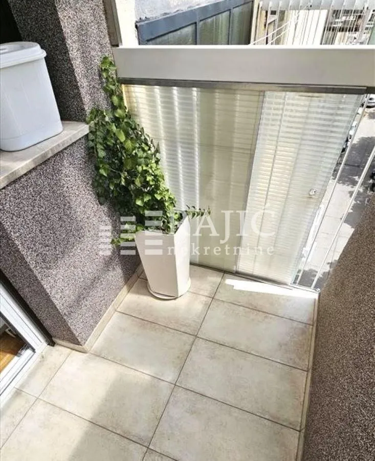 Manji popločani balkon sa saksijom i ukrasnom biljkom.