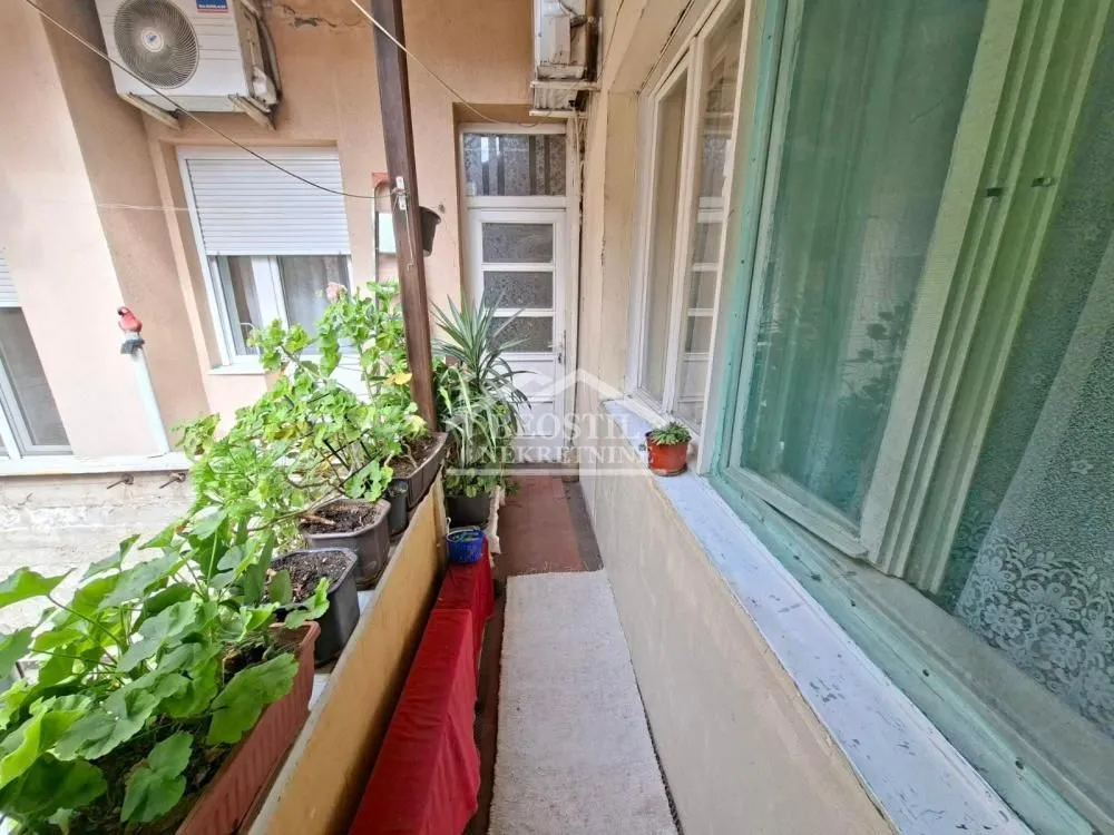 Uski balkon sa saksijama i pogledom na unutrašnje dvorište.