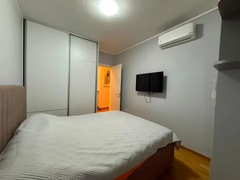 Namještena spavaća soba sa bračnim krevetom, ugradnim ormarom, klima uređajem i televizorom na zidu. - image 7