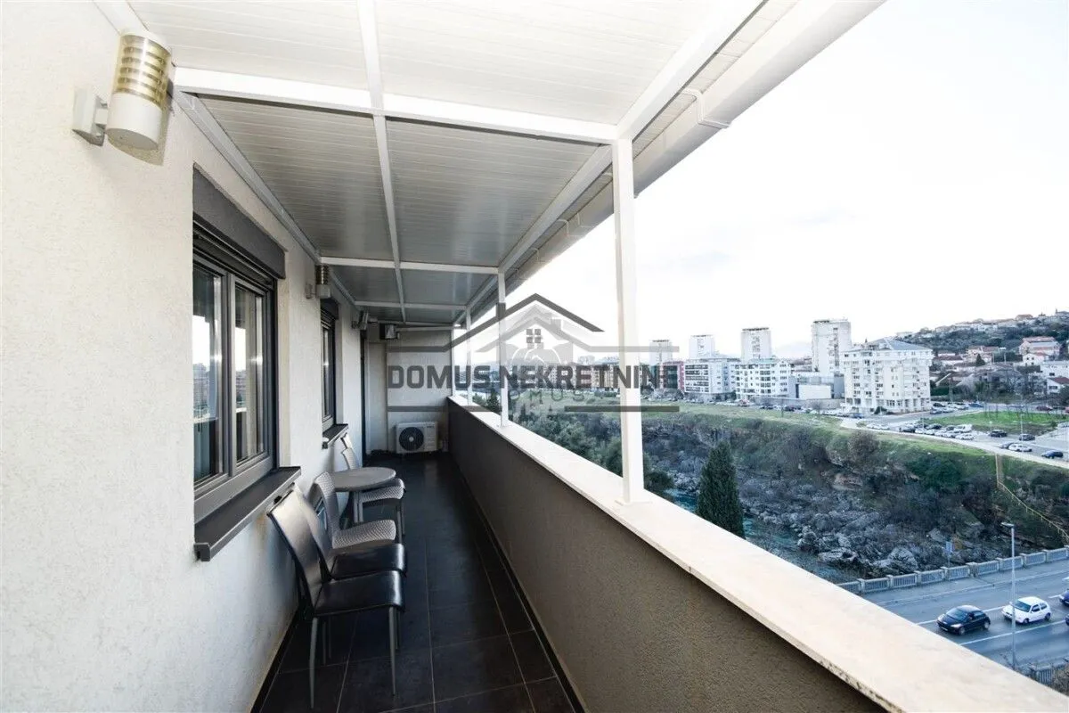 Natkriveni balkon sa garniturom za sjedenje i pogledom na grad.