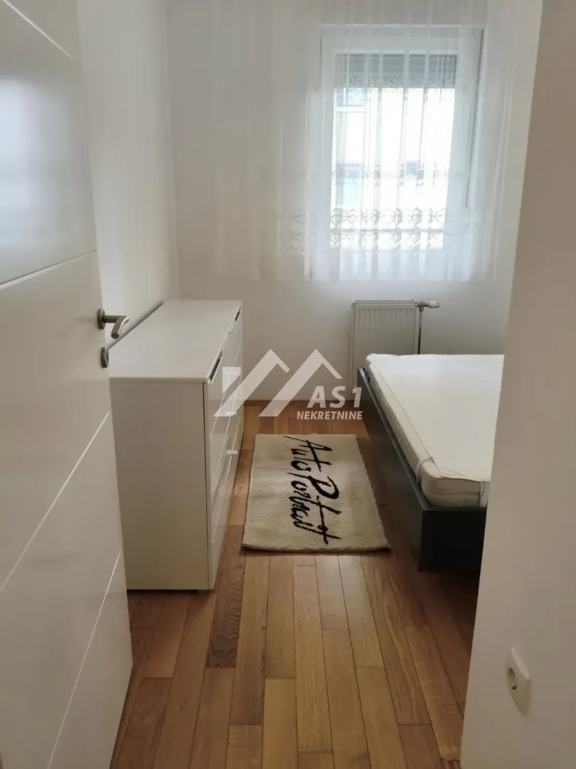 Manja spavaća soba sa krevetom, komodom i prozorom.