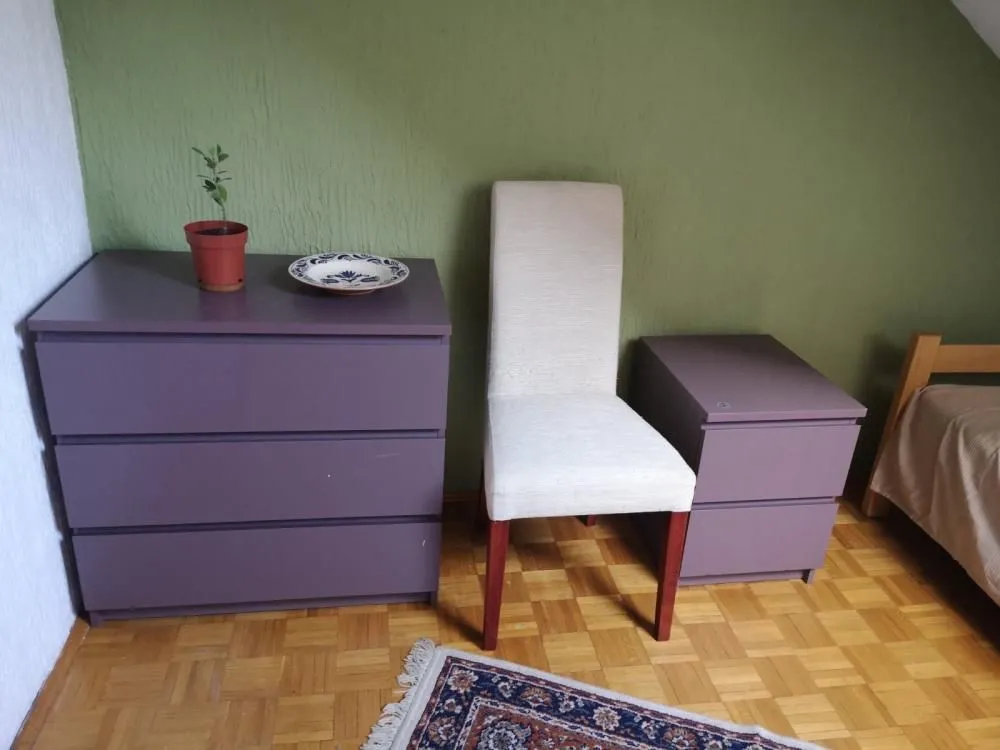 View of a part of the bedroom with a dresser, a chair, and a bed.