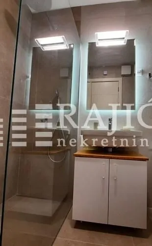 Modern bathroom with a sink, mirror, and walk-in shower.