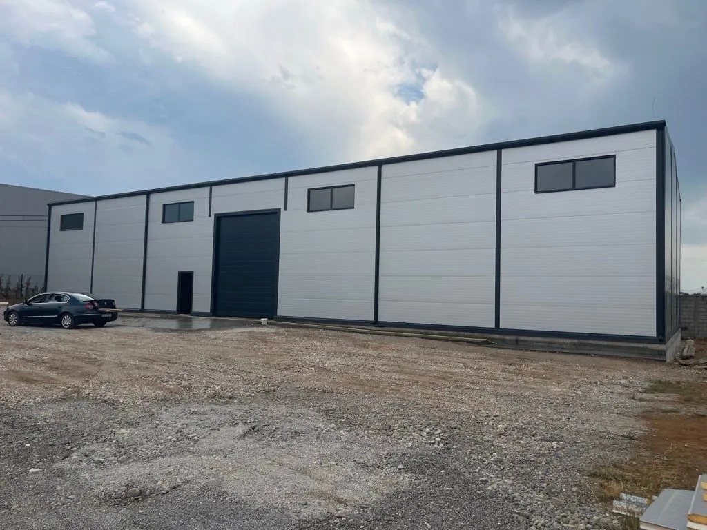 Exterior of a modern business or industrial building with large doors and parking space.