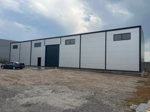 Exterior of a modern business or industrial building with large doors and parking space. - image 2