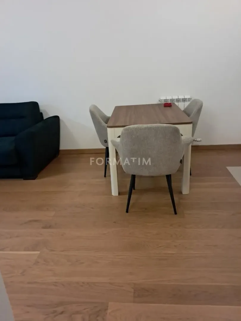 Dining table with chairs and part of the living room with a sofa.