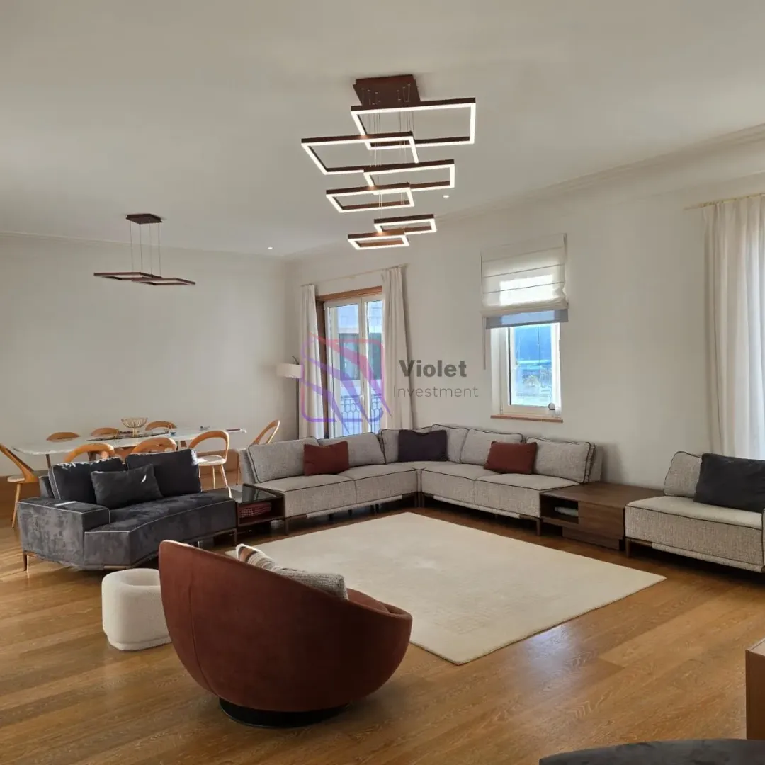 Spacious living room with a sofa set, dining area, and modern lighting.